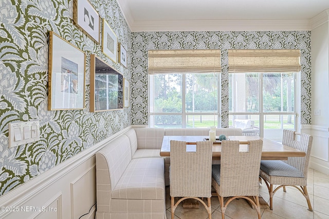 tiled dining area featuring wallpapered walls, wainscoting, and ornamental molding