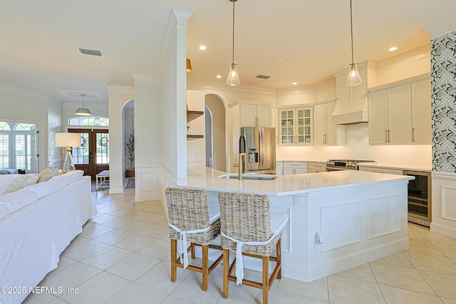 kitchen featuring a sink, stainless steel appliances, visible vents, arched walkways, and beverage cooler