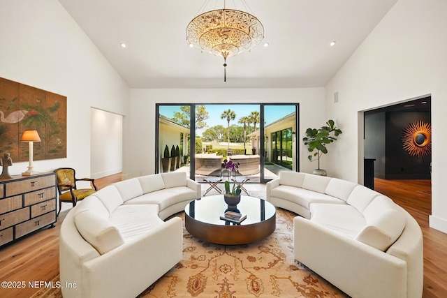 living area featuring an inviting chandelier, recessed lighting, wood finished floors, and high vaulted ceiling