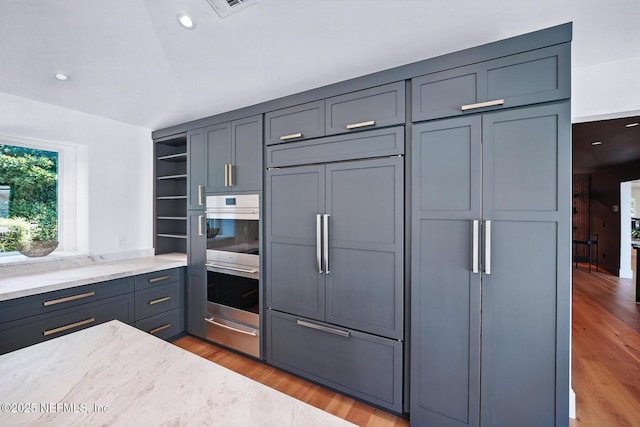 kitchen with paneled refrigerator, open shelves, light wood-type flooring, double oven, and a warming drawer