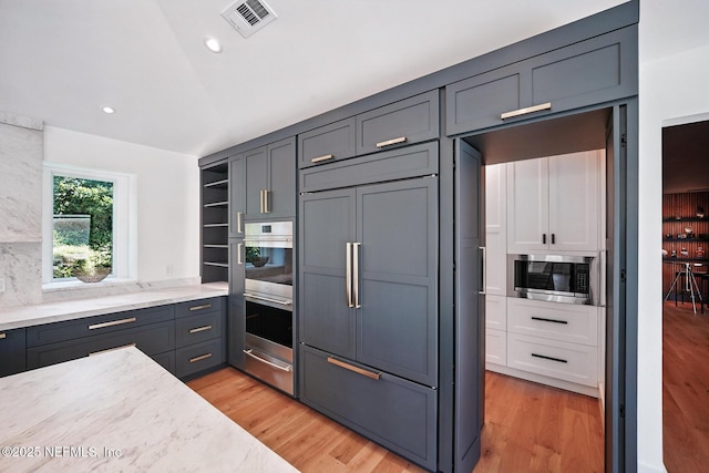 kitchen with visible vents, open shelves, built in appliances, light stone countertops, and a warming drawer