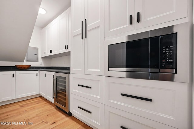 bar with beverage cooler, light wood-style floors, and built in microwave