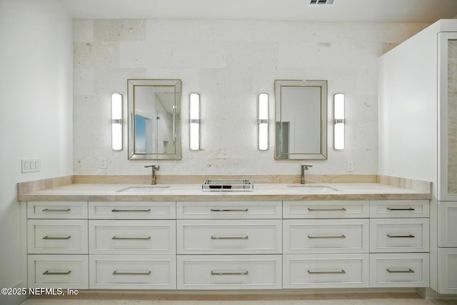 full bath featuring double vanity, visible vents, and a sink