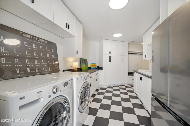 laundry area featuring separate washer and dryer, cabinet space, and light floors
