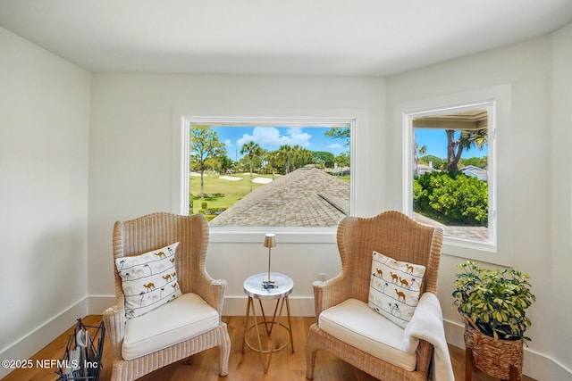 sitting room featuring golf course view and wood finished floors