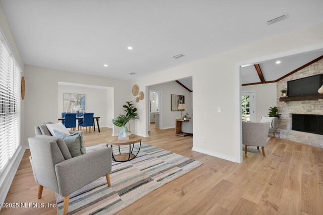 living room featuring visible vents, a brick fireplace, light wood-style floors, baseboards, and recessed lighting