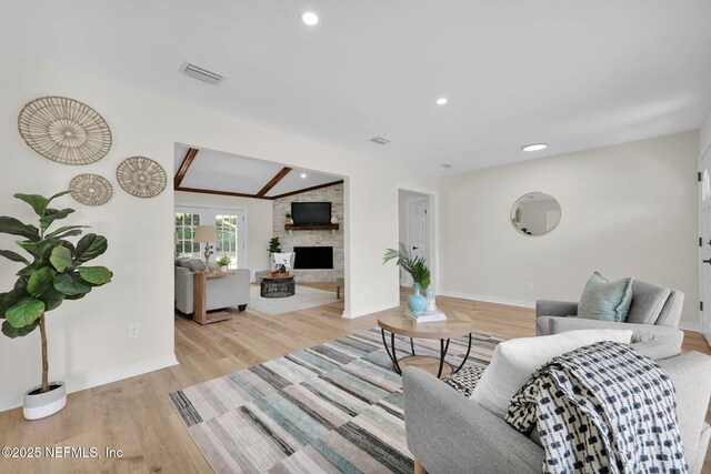 living area with baseboards, visible vents, a large fireplace, and light wood-type flooring