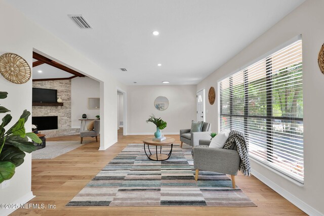 living room with a healthy amount of sunlight, light wood-style floors, a stone fireplace, and visible vents