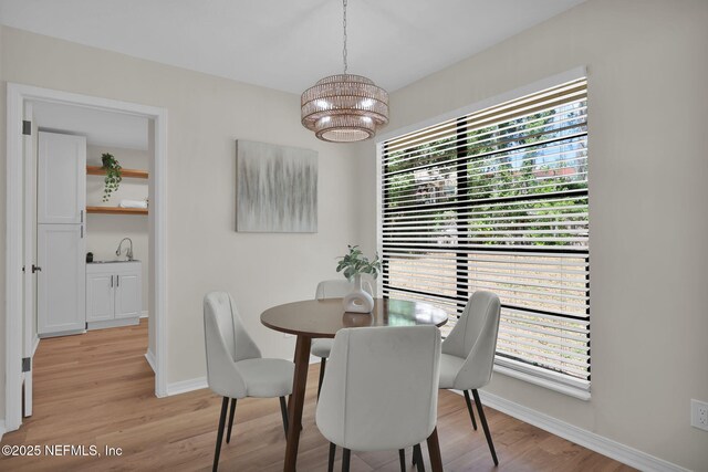 dining room featuring an inviting chandelier, light wood finished floors, baseboards, and a wealth of natural light