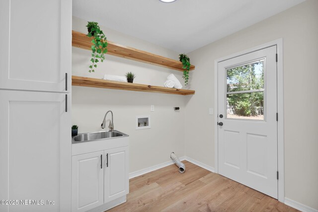 clothes washing area featuring baseboards, a sink, cabinet space, light wood finished floors, and hookup for an electric dryer