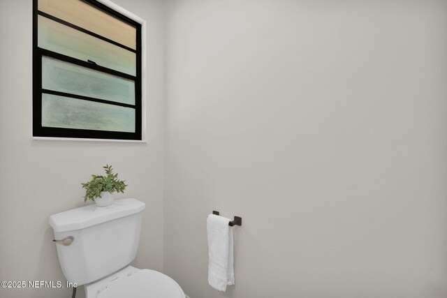 bathroom with baseboards, a wealth of natural light, and toilet