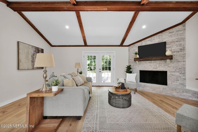 living room featuring french doors, lofted ceiling with beams, wood finished floors, and a fireplace