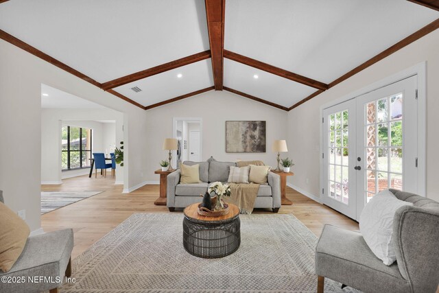 living area with vaulted ceiling with beams, french doors, and light wood-style flooring