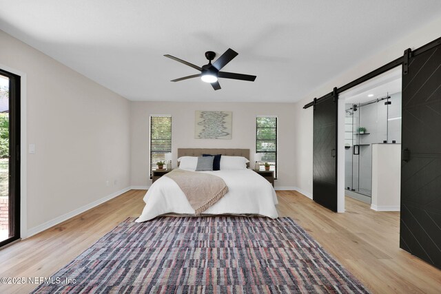 bedroom featuring light wood-type flooring, a barn door, baseboards, and access to exterior