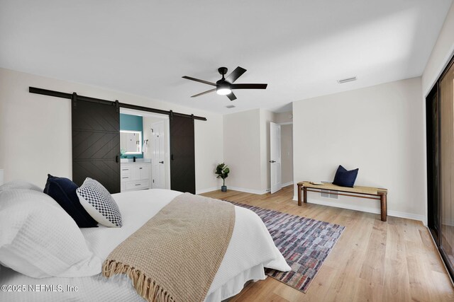 bedroom featuring baseboards, a ceiling fan, a barn door, and wood finished floors
