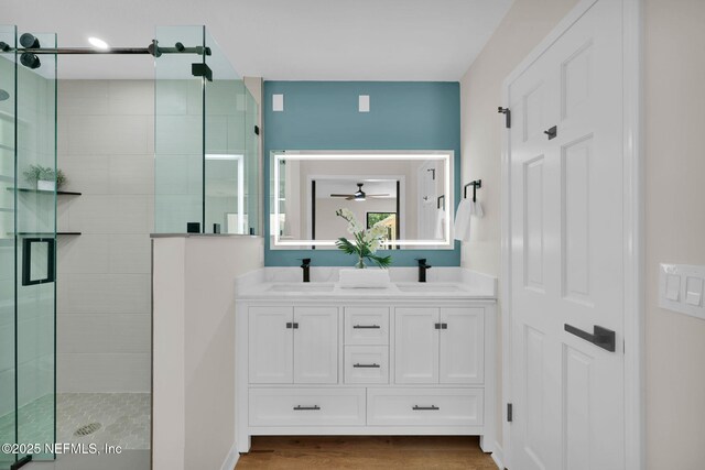 full bath with a ceiling fan, a shower stall, and a sink