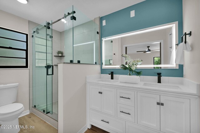 bathroom featuring toilet, ceiling fan, a sink, and wood finished floors