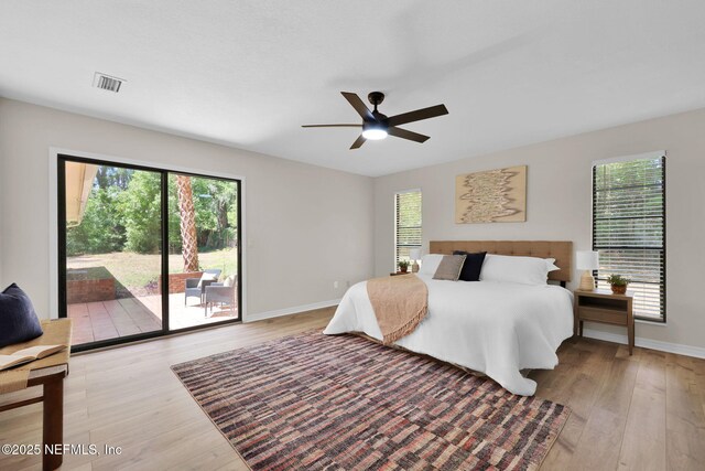 bedroom featuring light wood-style floors, access to outside, multiple windows, and visible vents