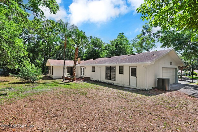 back of house featuring an attached garage, central air condition unit, and driveway