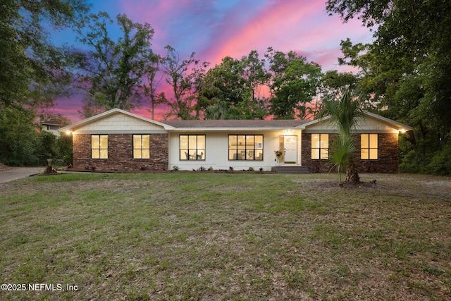 ranch-style home featuring brick siding and a front yard