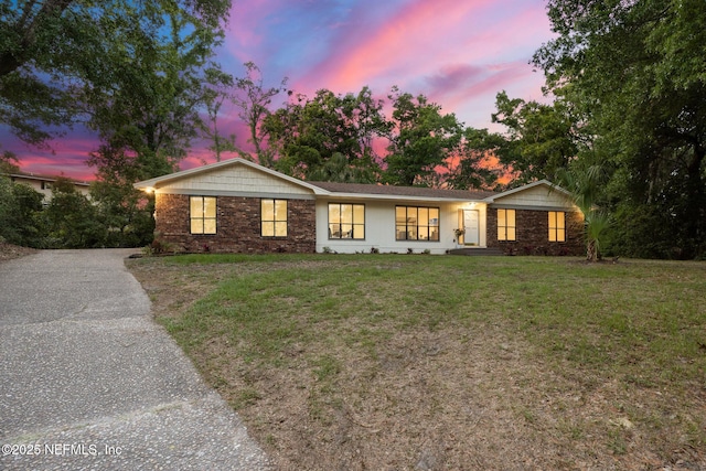 ranch-style house featuring a yard and aphalt driveway