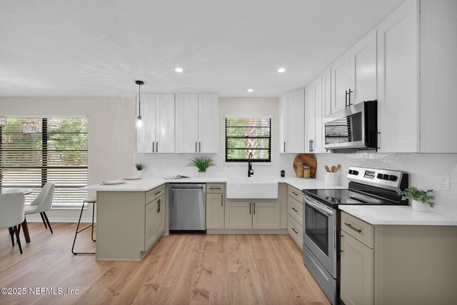 kitchen featuring backsplash, a peninsula, appliances with stainless steel finishes, and a sink