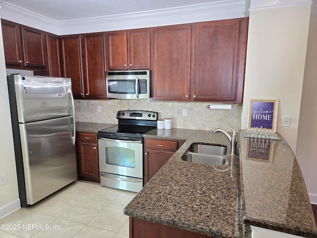 kitchen featuring dark brown cabinets, a sink, dark stone countertops, a peninsula, and stainless steel appliances