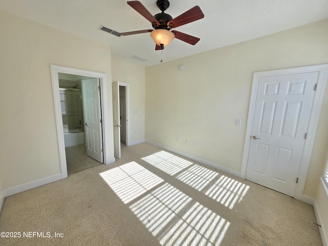 unfurnished bedroom with baseboards, light colored carpet, ensuite bathroom, and visible vents