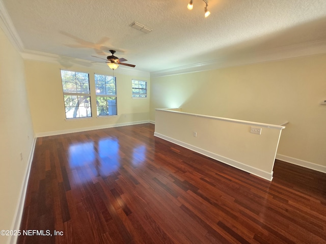 empty room featuring visible vents, ornamental molding, ceiling fan, a textured ceiling, and dark wood finished floors