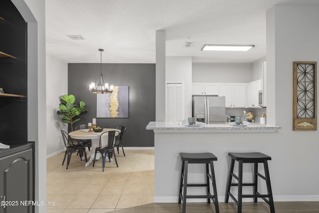 8601 Beach Blvd Unit 323, Jacksonville, FL 32216 - kitchen with an inviting chandelier, a peninsula, a breakfast bar, stainless steel fridge, and white cabinetry