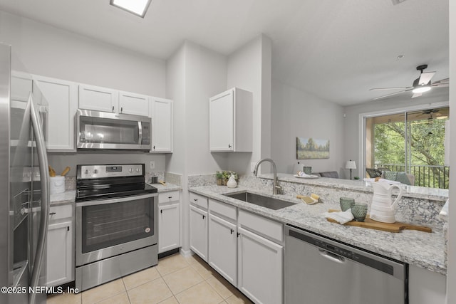 8601 Beach Blvd Unit 323, Jacksonville, FL 32216 - kitchen with appliances with stainless steel finishes, a sink, light tile patterned floors, light stone counters, and white cabinets