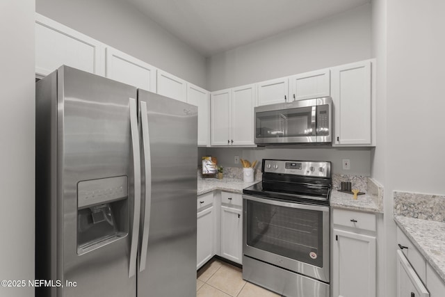 8601 Beach Blvd Unit 323, Jacksonville, FL 32216 - kitchen featuring appliances with stainless steel finishes, light tile patterned floors, white cabinets, and light stone countertops