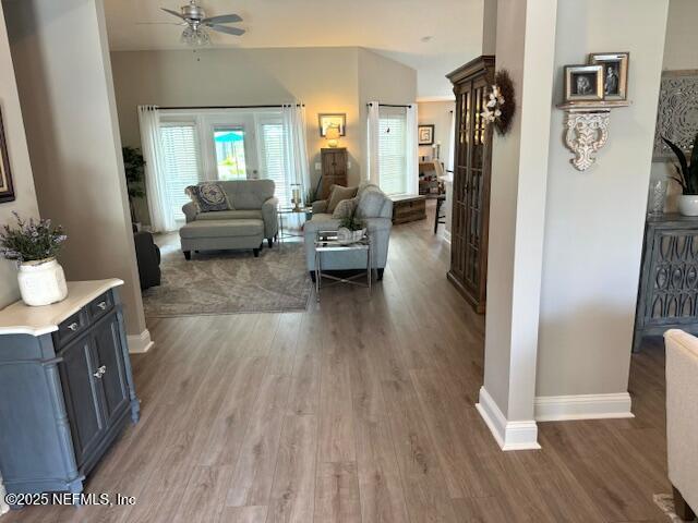 living area featuring baseboards, a ceiling fan, and wood finished floors