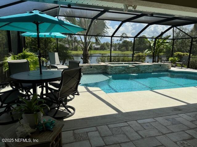 view of swimming pool with a lanai, a patio, a pool with connected hot tub, and a water view