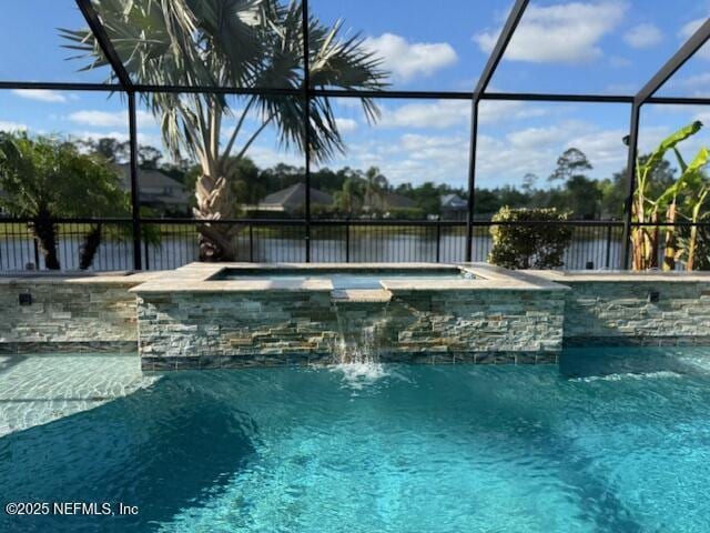 pool with glass enclosure, a water view, and an in ground hot tub