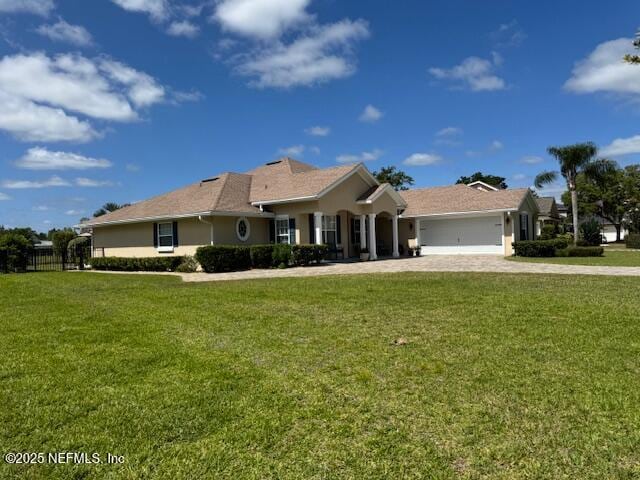 ranch-style home with decorative driveway, an attached garage, and a front lawn
