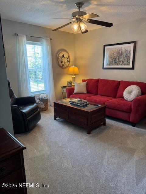 living room featuring ceiling fan, carpet, and a textured ceiling