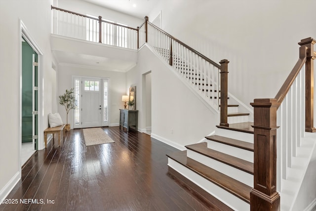 entryway featuring crown molding, hardwood / wood-style flooring, baseboards, a high ceiling, and stairs