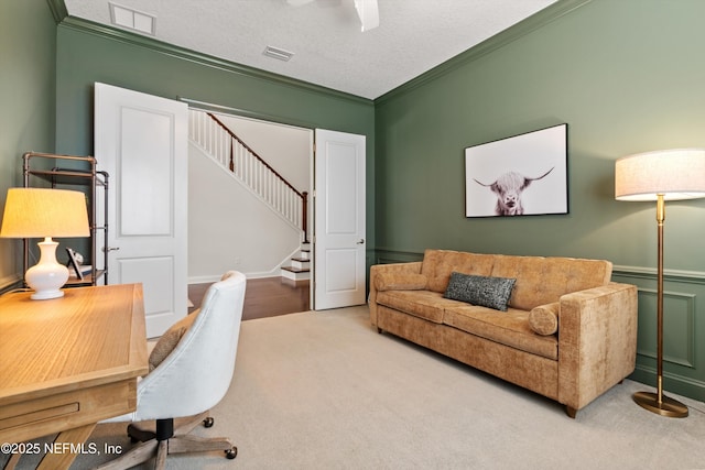 carpeted home office featuring a textured ceiling, ceiling fan, visible vents, and ornamental molding