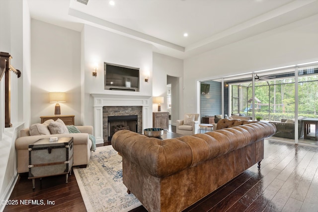 living area with visible vents, a tray ceiling, dark wood-style floors, and a fireplace