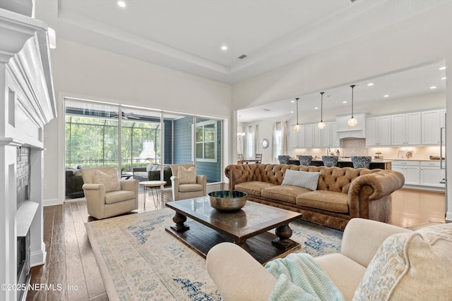 living room with a towering ceiling, recessed lighting, wood-type flooring, and a fireplace