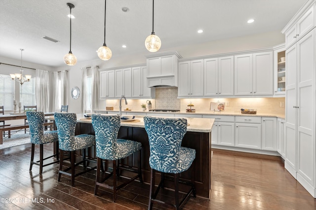 kitchen with gas cooktop, a breakfast bar area, dark wood-style flooring, tasteful backsplash, and white cabinetry