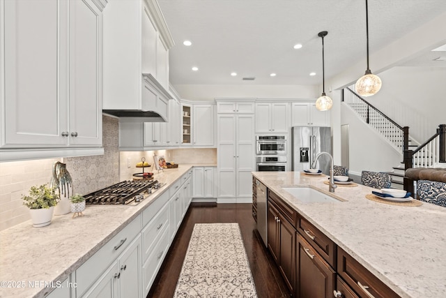 kitchen featuring white cabinets, dark brown cabinets, a sink, dark wood finished floors, and stainless steel appliances