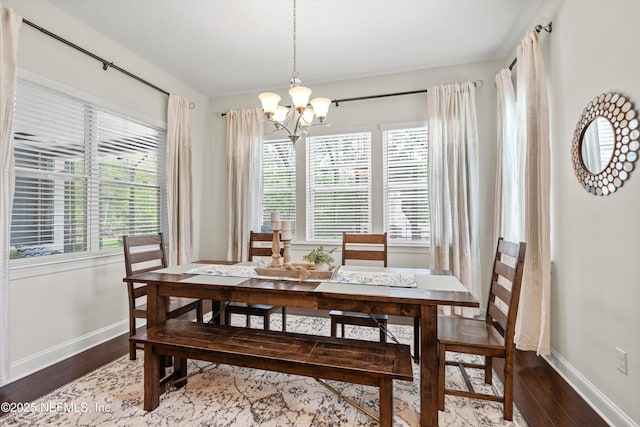 dining room featuring baseboards, wood finished floors, and a notable chandelier