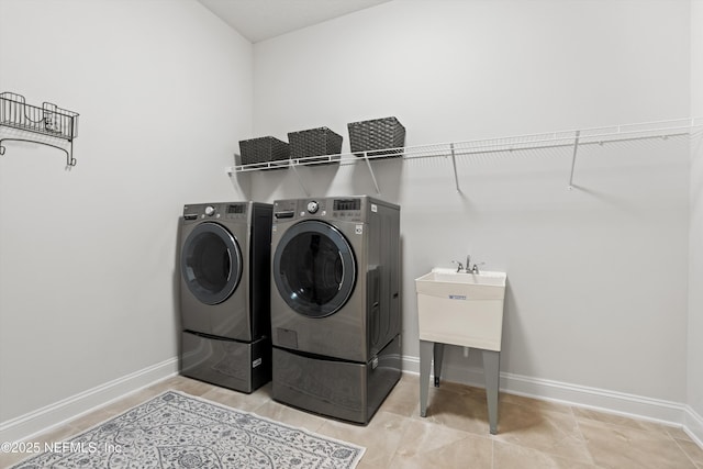 clothes washing area featuring laundry area, baseboards, and washing machine and clothes dryer