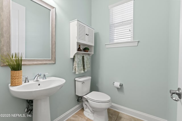 bathroom with toilet, baseboards, and tile patterned flooring