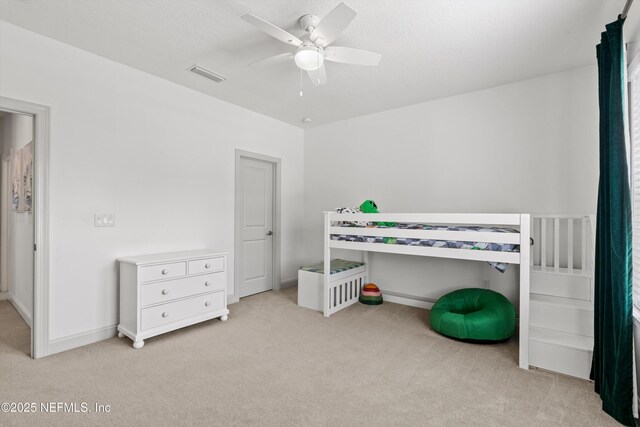 unfurnished bedroom featuring baseboards, ceiling fan, light colored carpet, and visible vents