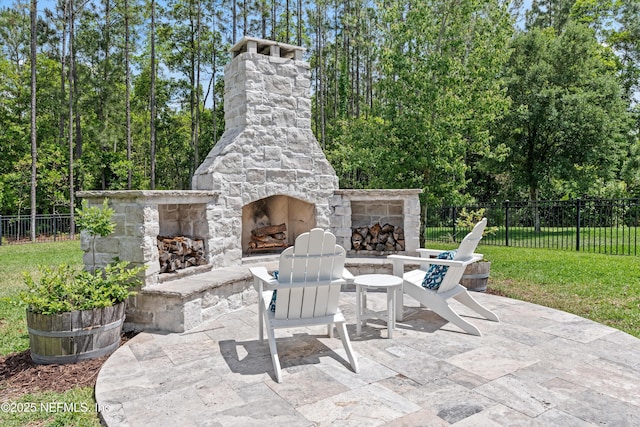 view of patio / terrace with an outdoor stone fireplace and fence