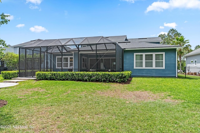rear view of house with a yard, fence, a shingled roof, and glass enclosure