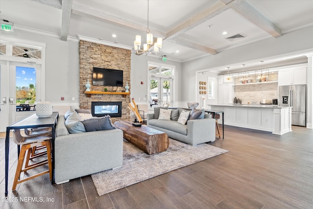 living area with a notable chandelier, a fireplace, beamed ceiling, visible vents, and dark wood-style floors